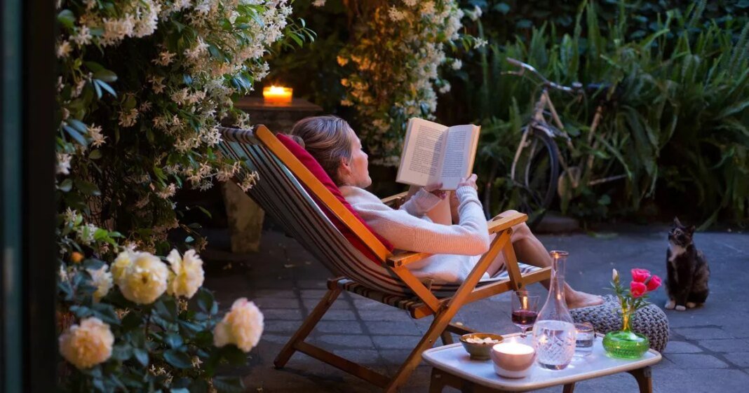 1_woman-relaxing-on-deck-chair-in-back-yard-reading-a-book-with-her-cat-watching